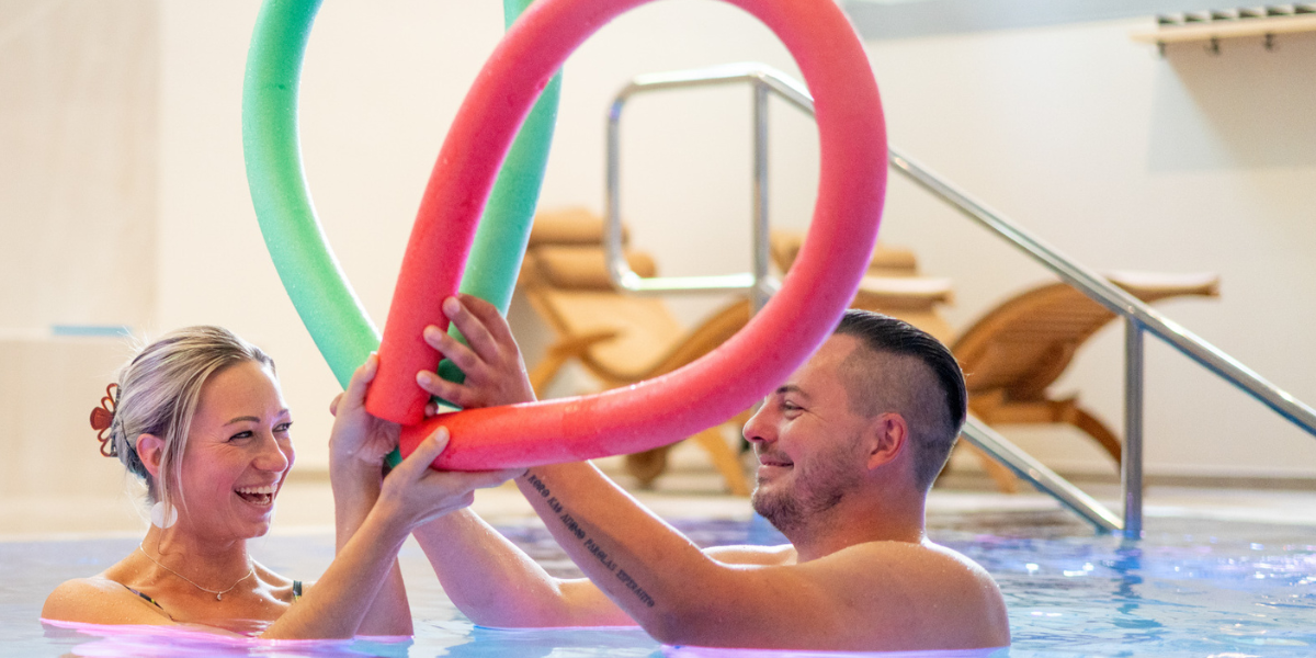 Ein Paar mit Schwimmnudeln im Pool des Kongresshotels