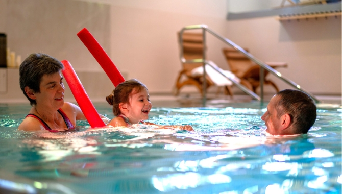 Pool im Kongresshotel Potsdam. Urlaub. Familie. Oma und Opa. Großeltern bringen Kindern das Schwimmen bei.