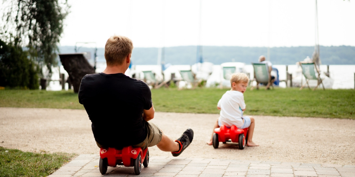 Vater und Sohn  fahren mit Spielzeugautos auf dem Weg direkt zur Freiluftbar beim Kongresshotel Potsdam.