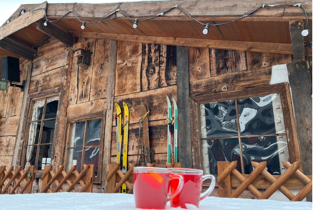 Gipfel Stüberl im Winter mit zwei dampfenden Teetassen auf einem Tisch.