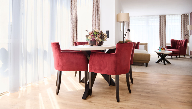 Superior Suite im Kongresshotel Potsdam mit modernem Essbereich und roten Samtstühlen.