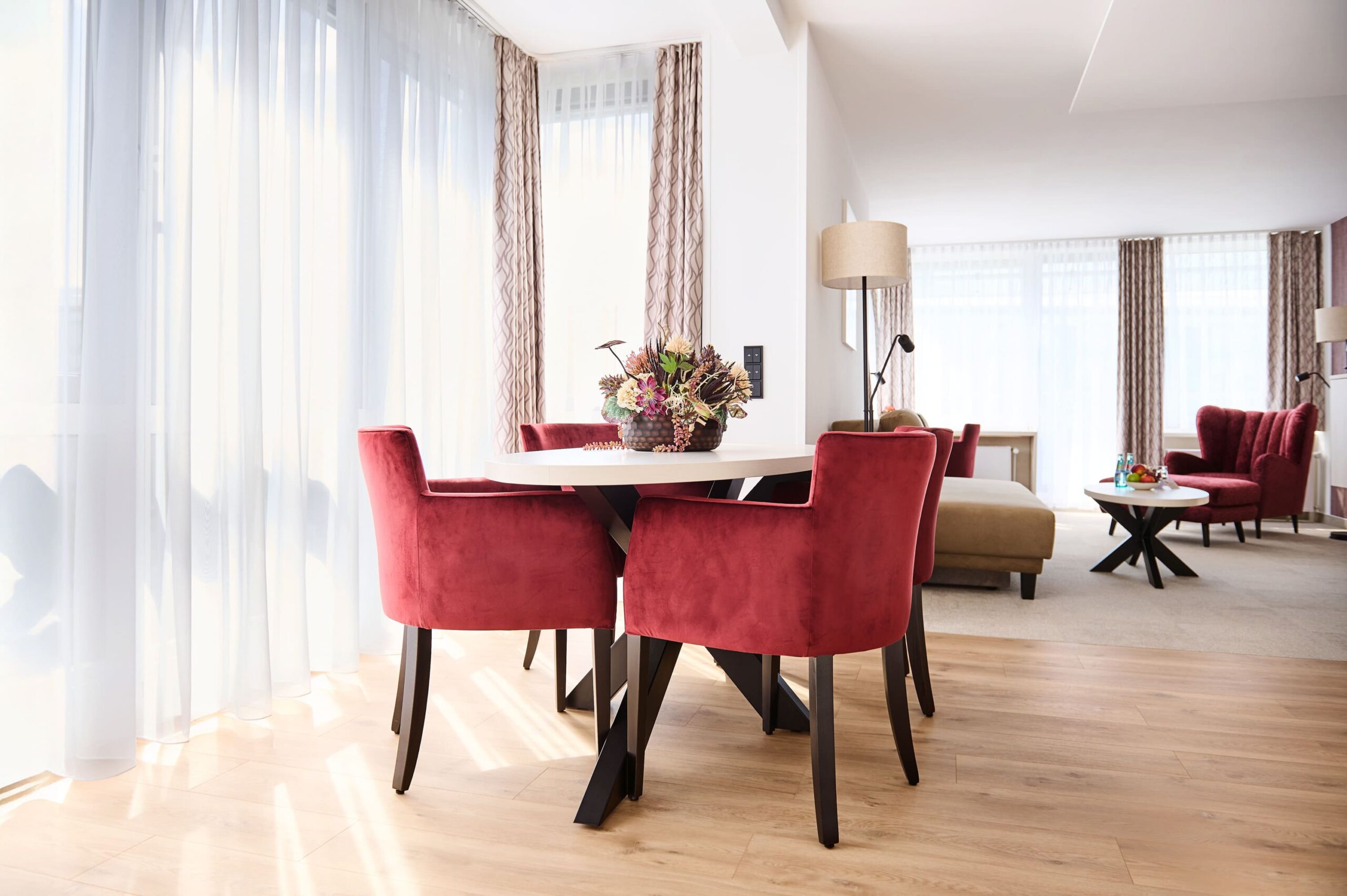 Superior Suite im Kongresshotel Potsdam mit modernem Essbereich und roten Samtstühlen.