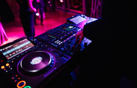 DJ bedient ein professionelles Mischpult bei einer Veranstaltung mit farbiger Beleuchtung.