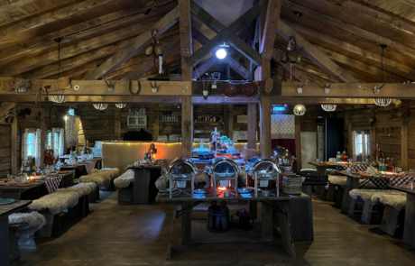 Rustikale Holzhütte mit gedeckten Tischen, Sitzbänken und Buffet für eine Veranstaltung.